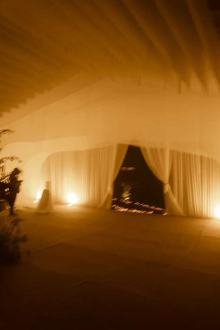 Entrada iluminada de noche entre telas doradas